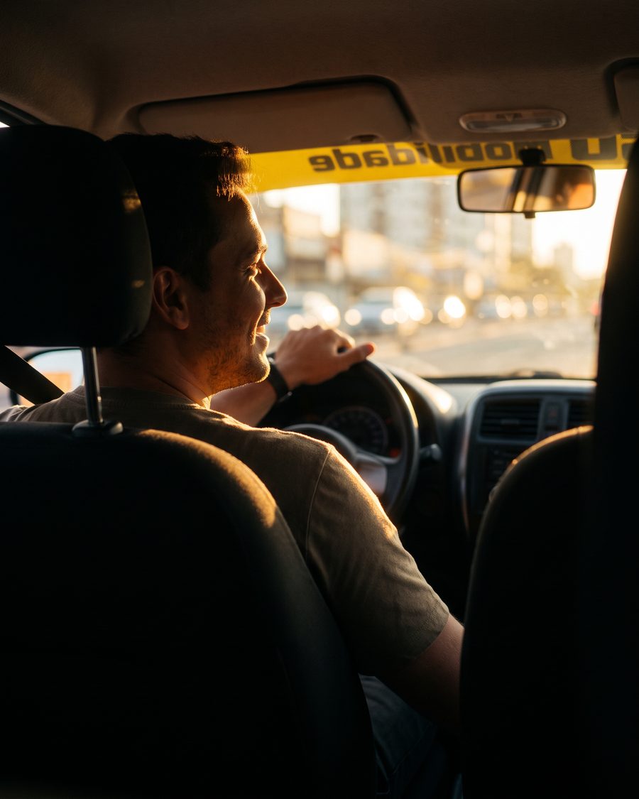Motorista ao volante de um carro da iGO Mobilidade em Marília, com a faixa da iGO no para-brisa